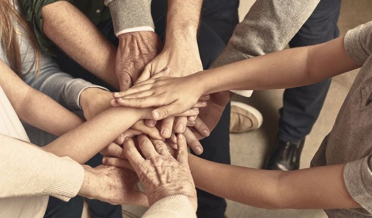 A group of people are putting their hands together.