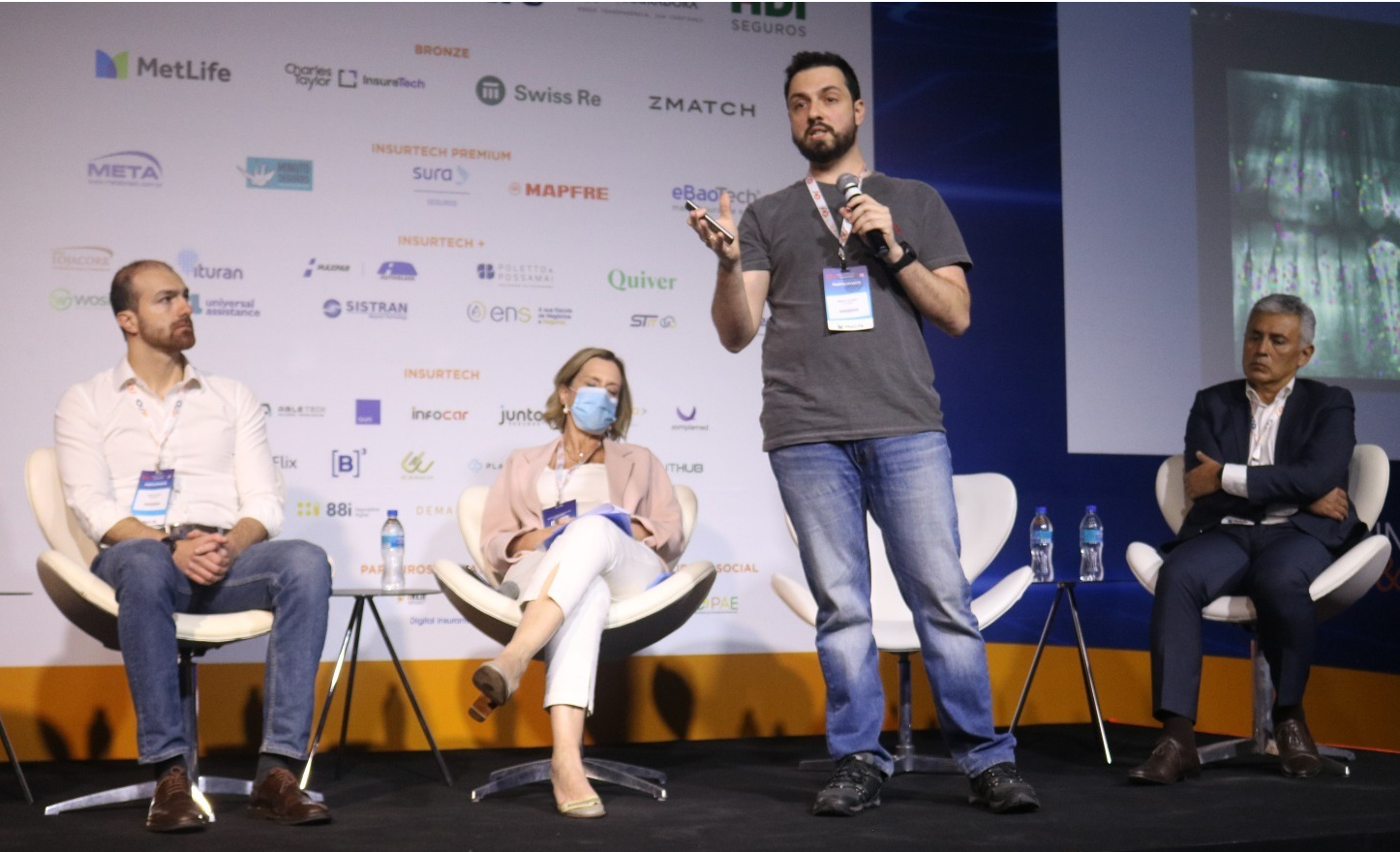 Um homem está fazendo uma apresentação para um grupo de pessoas sentadas em cadeiras.