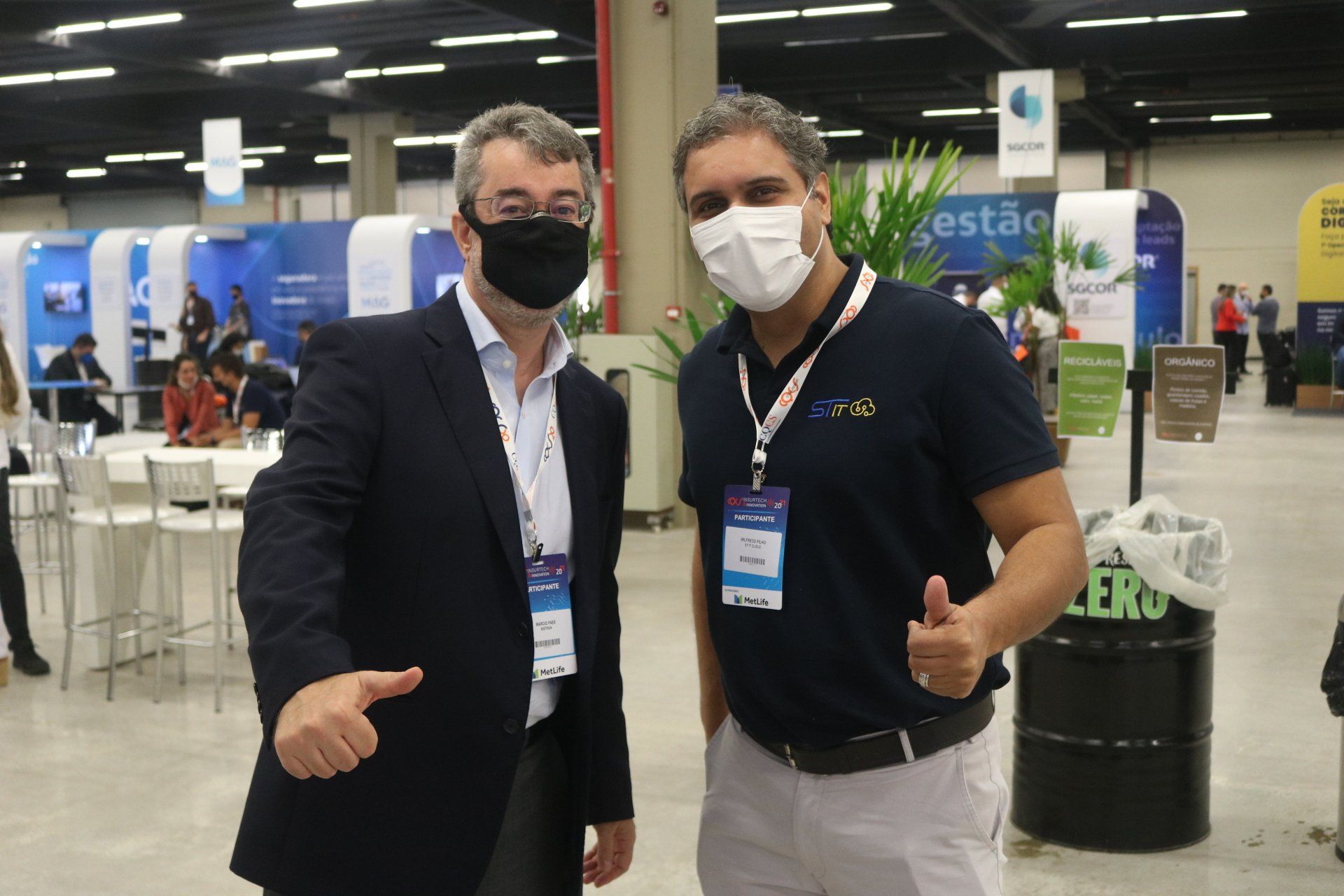 Dois homens usando máscaras estão parados um ao lado do outro em uma sala.