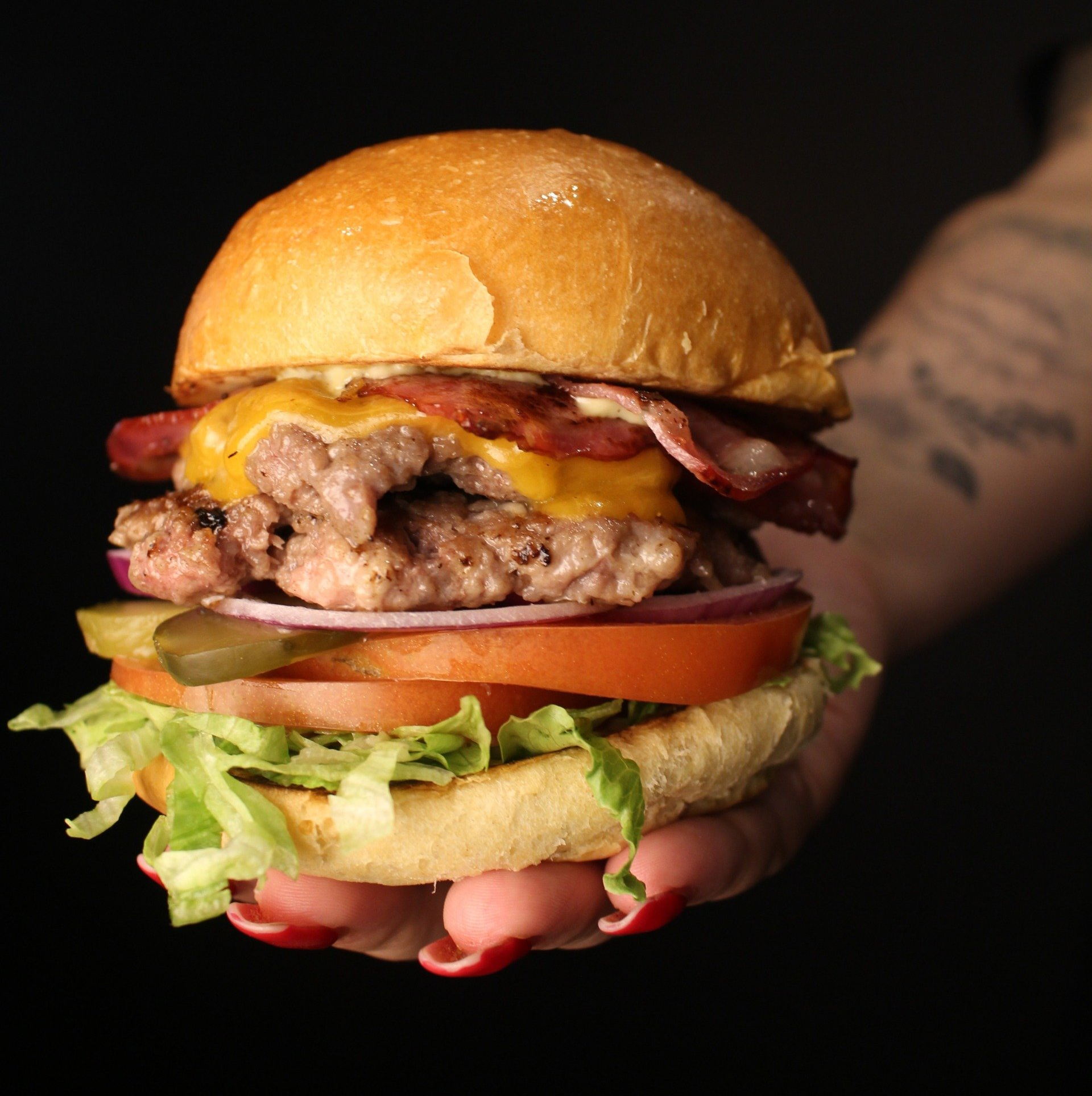 Um close de uma pessoa segurando um hambúrguer