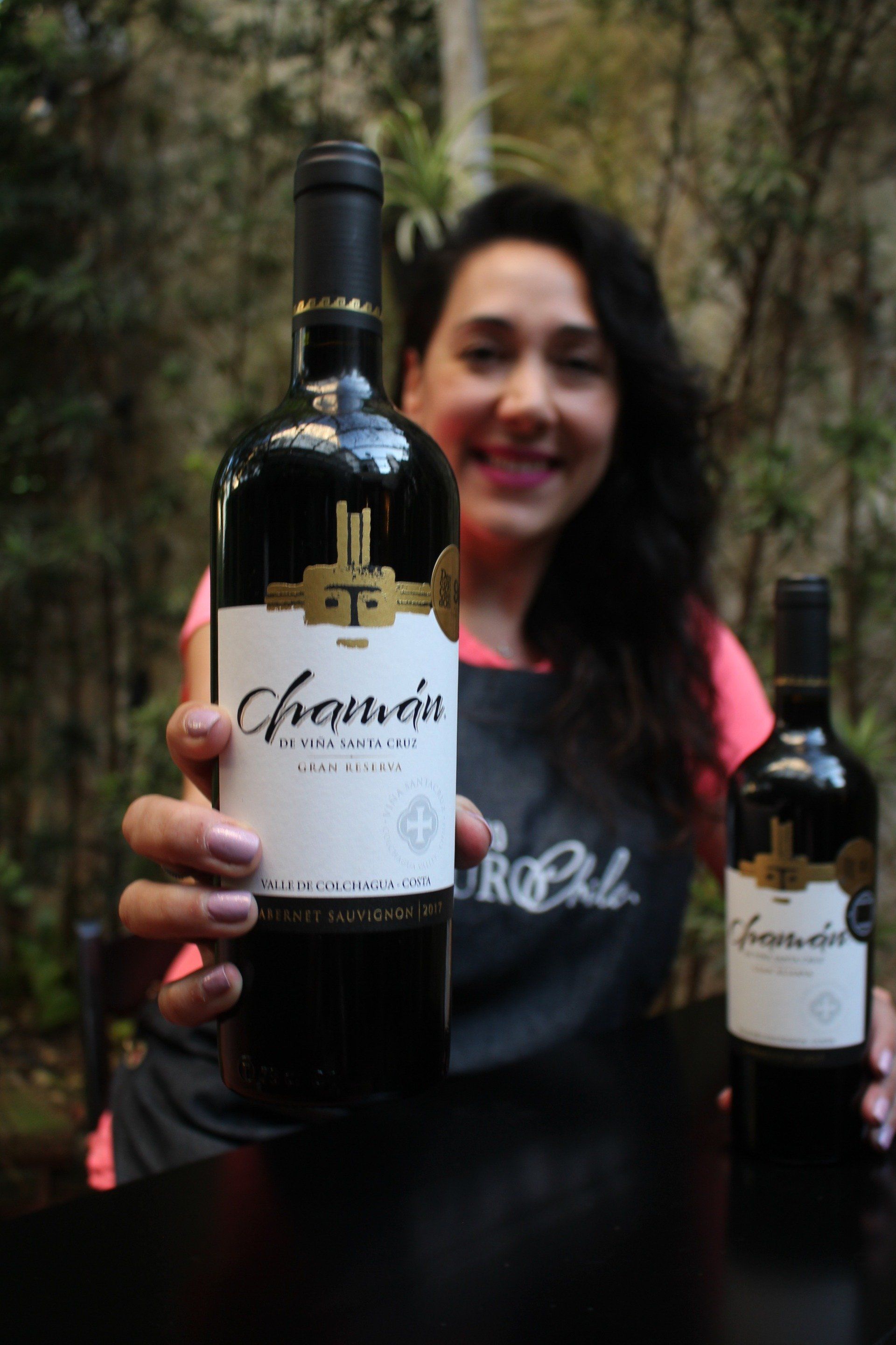 Uma mulher de avental está segurando uma garrafa de vinho