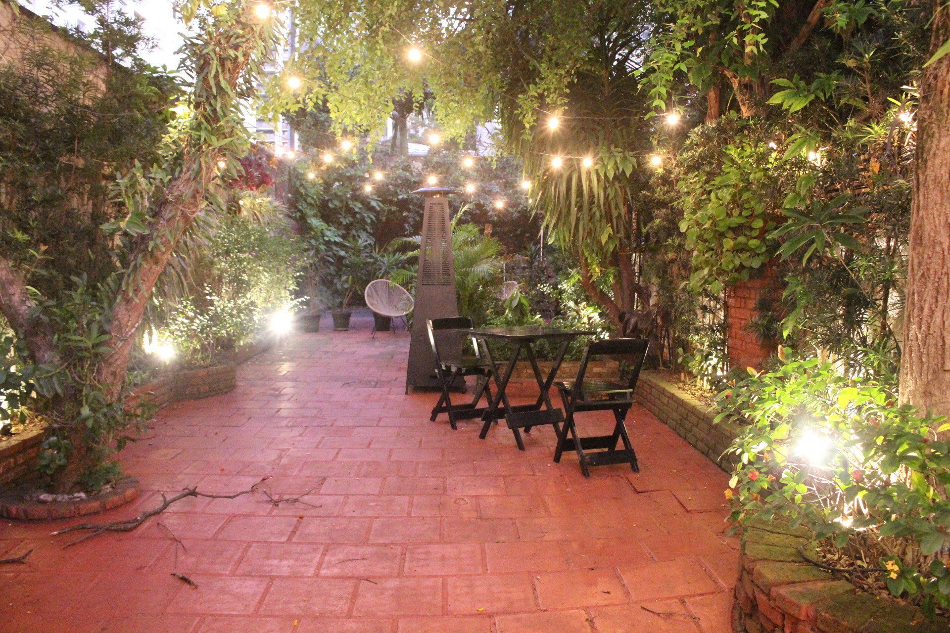 Um pátio com mesa e cadeiras e luzes penduradas nas árvores.