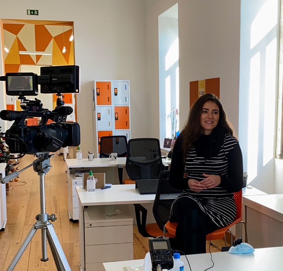 Uma mulher sentada na frente de uma câmera em um escritório