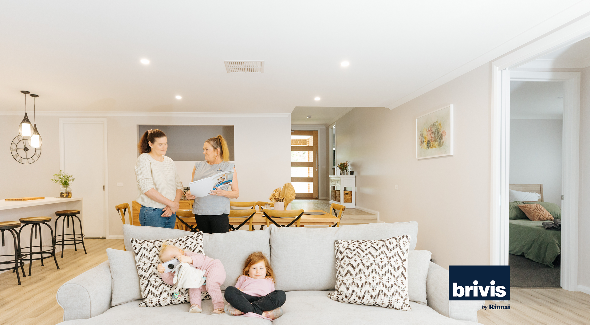 Family smiling in living room with Brivis by Rinnai logo in corner 