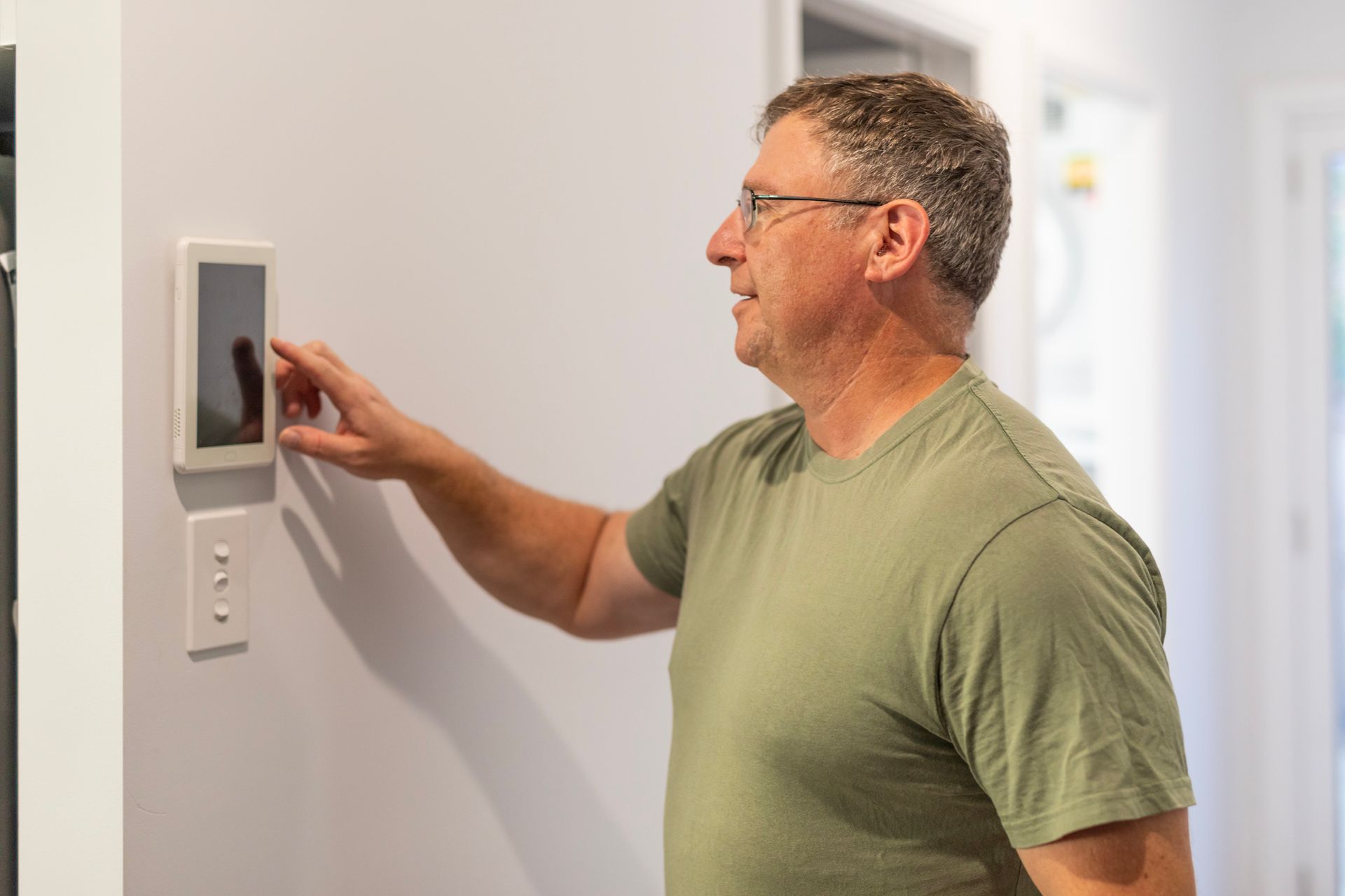 Man using smart air condition controller that sits on wall