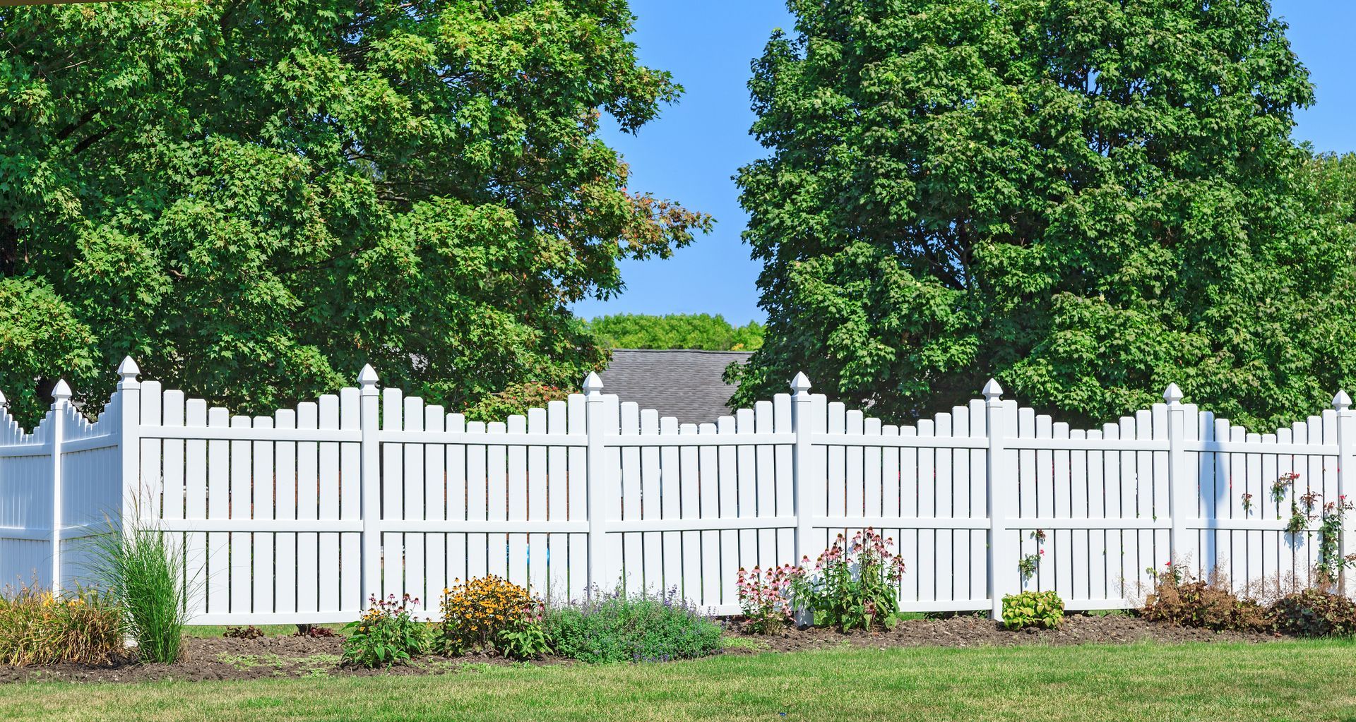 A White Picket Fence Surrounds a Lush Green Yard.