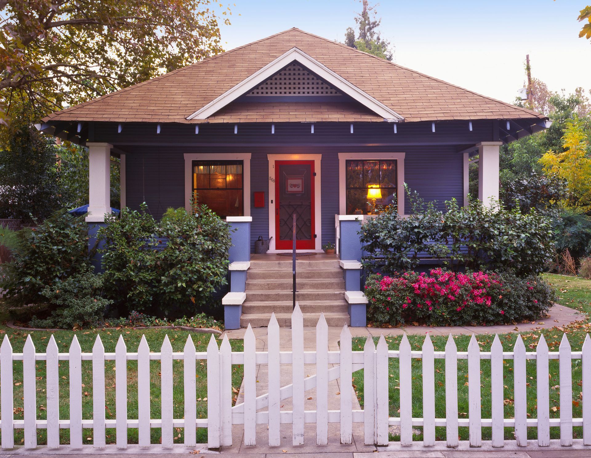 A blue house with a white picket fence around it