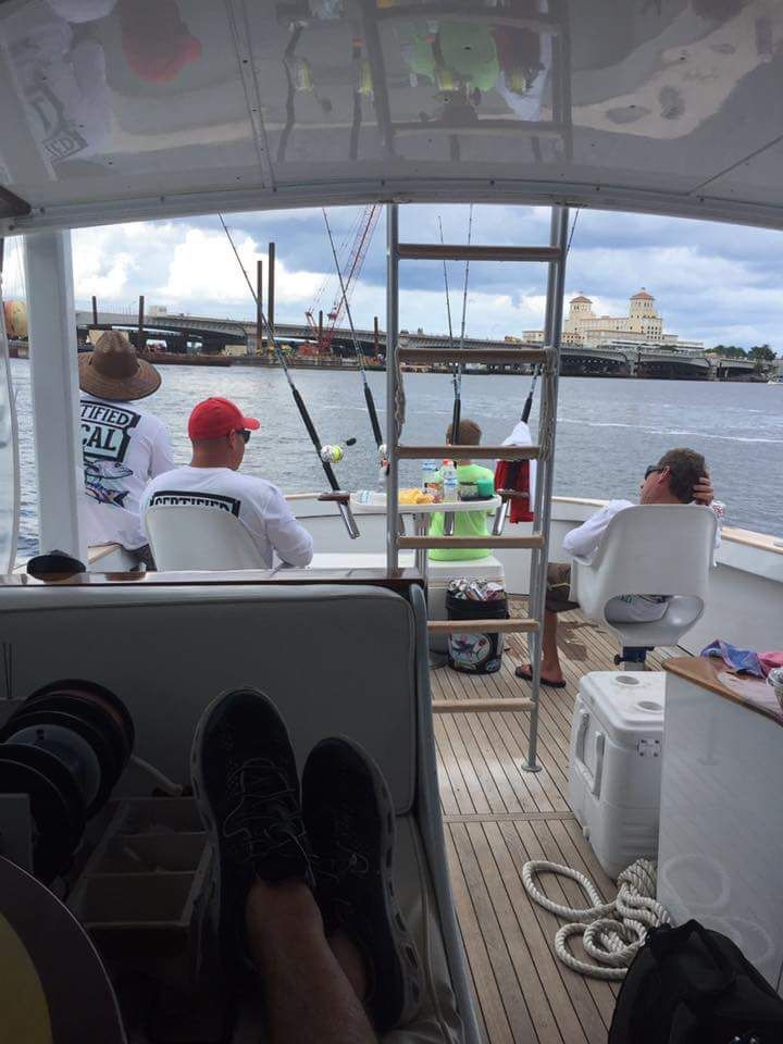 People on a fishing boat in calm water, with the photographer's feet visible in the foreground.