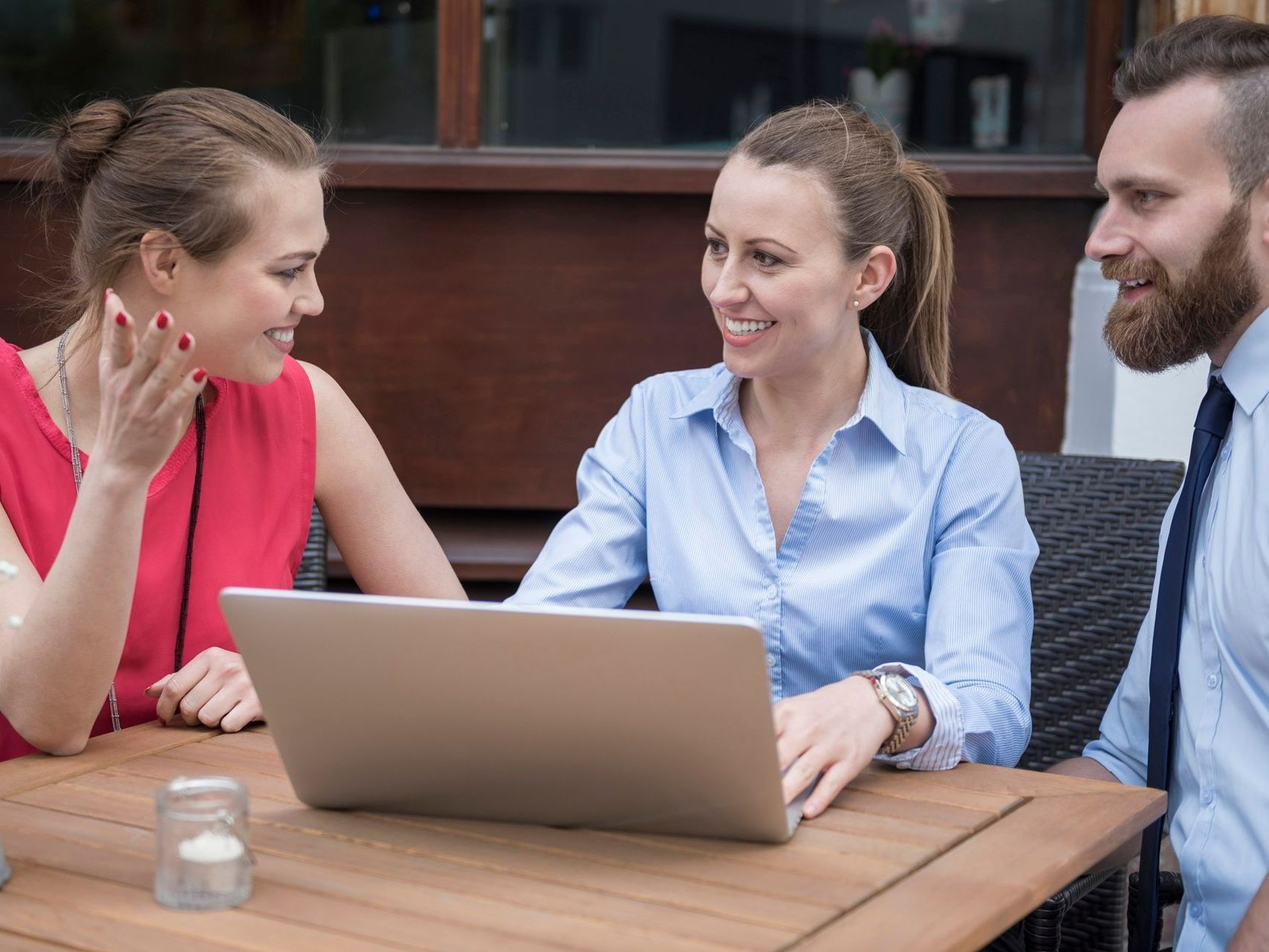 A group of people are sitting at a table looking at a laptop computer.