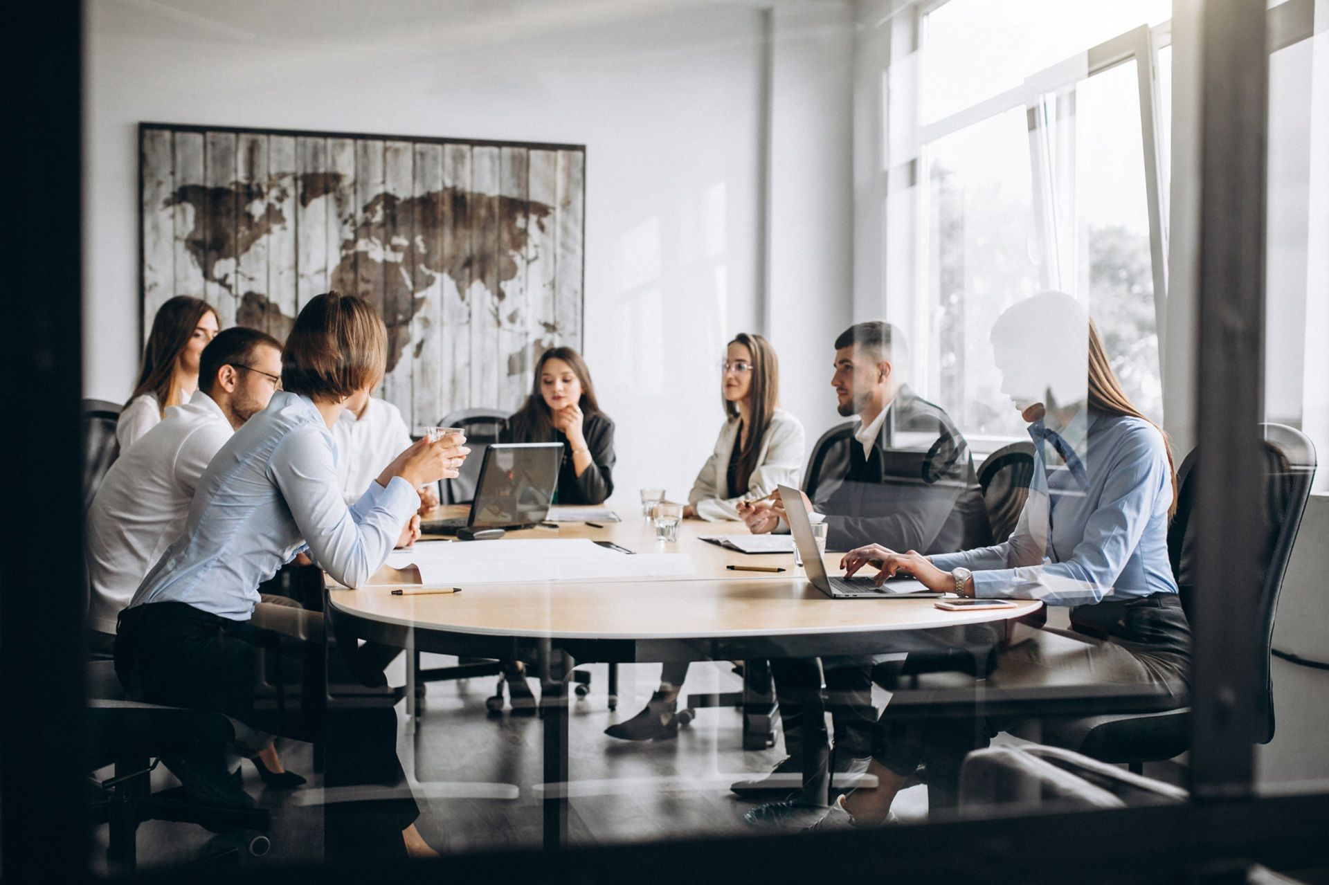 A group of people are sitting around a table in a conference room having a meeting.