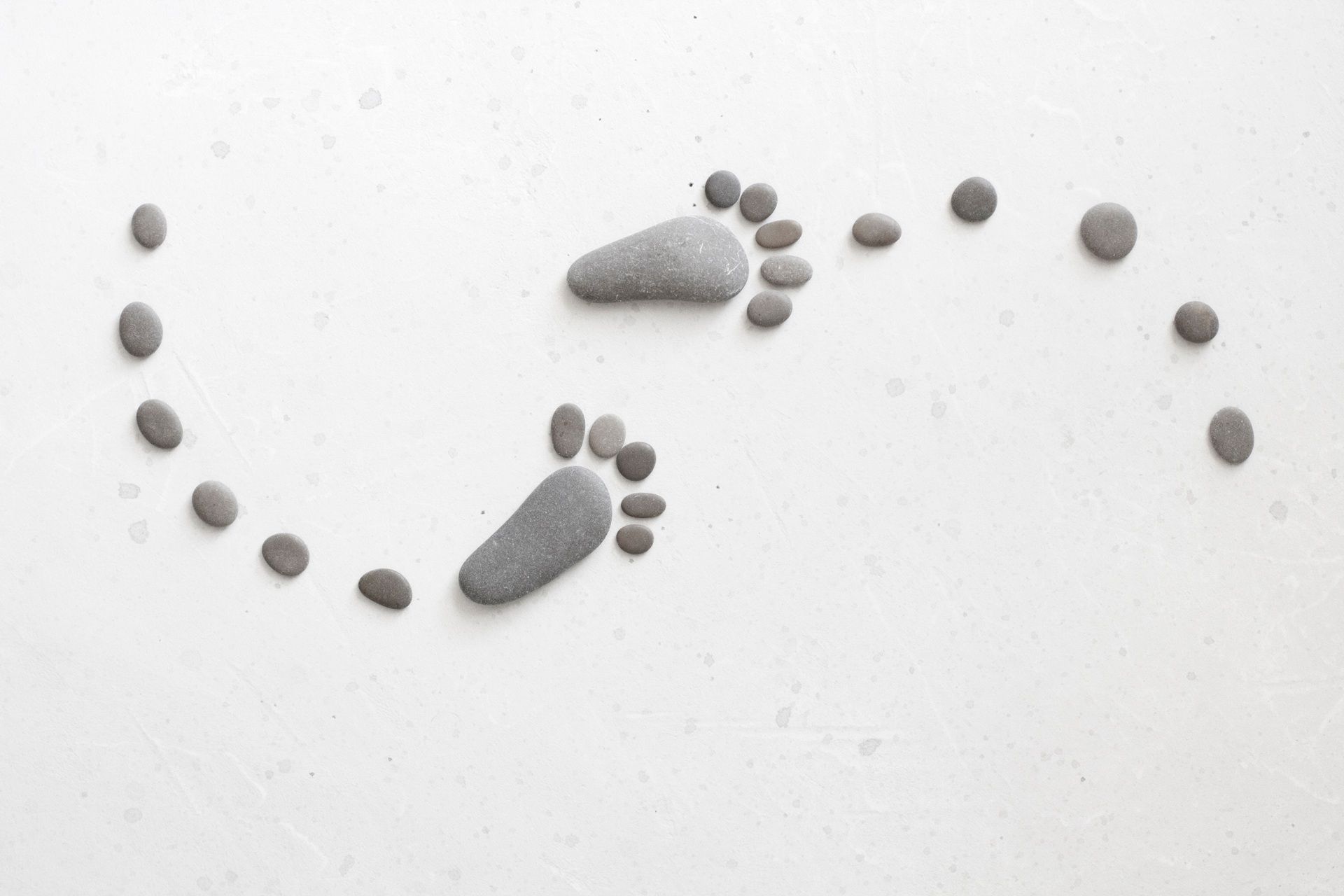 A pair of footprints made of rocks on a white surface.