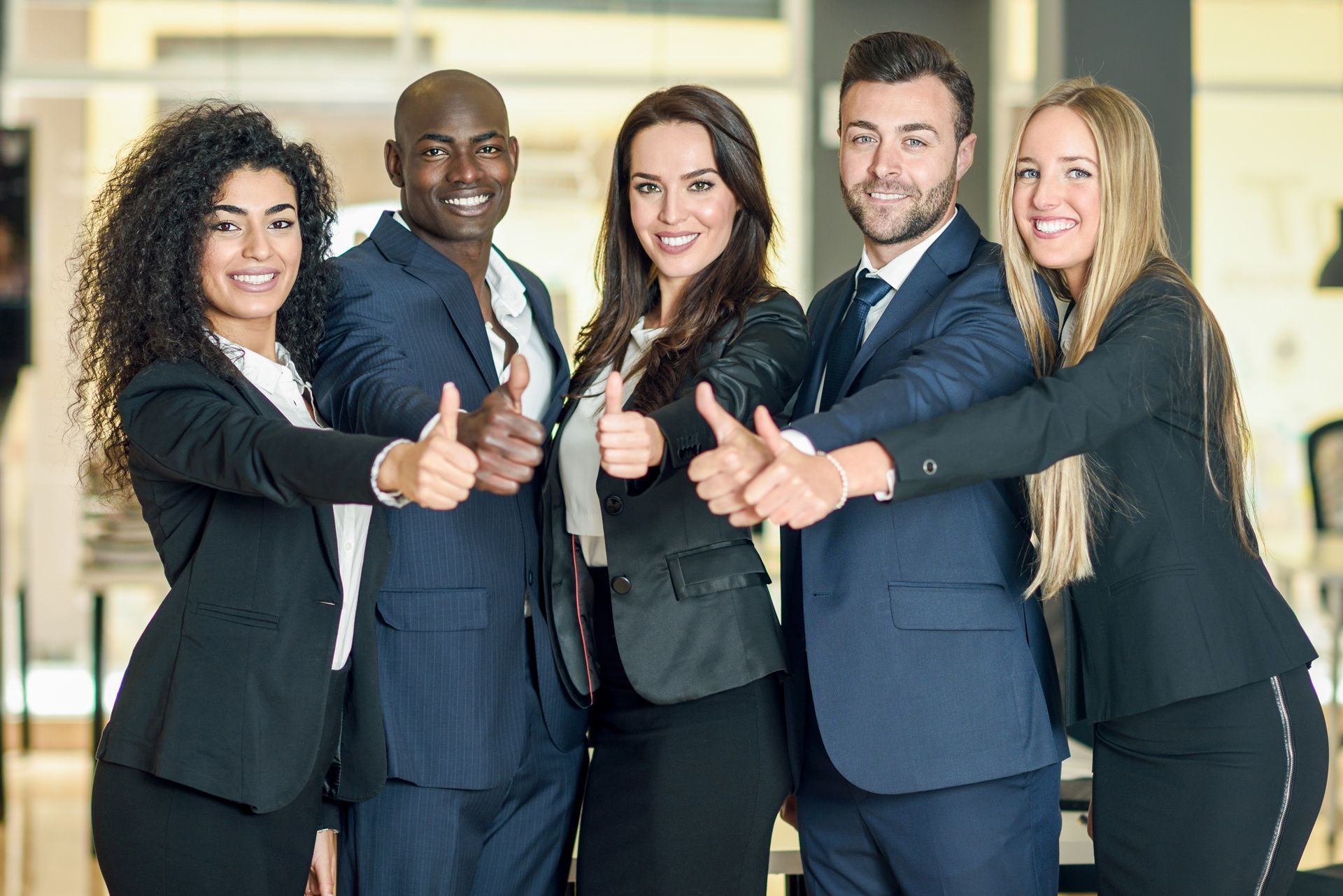 A group of business people are giving each other a thumbs up.