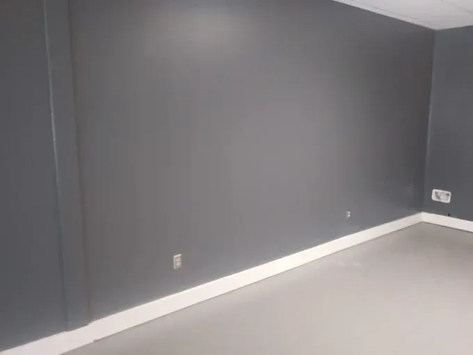 Empty room with gray walls, white baseboards, and light gray floor.