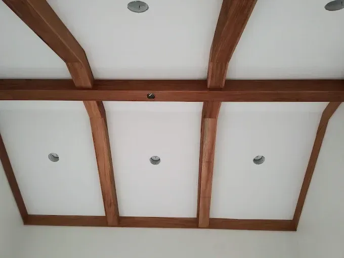 Ceiling with white panels framed by stained wood beams; recessed lights.