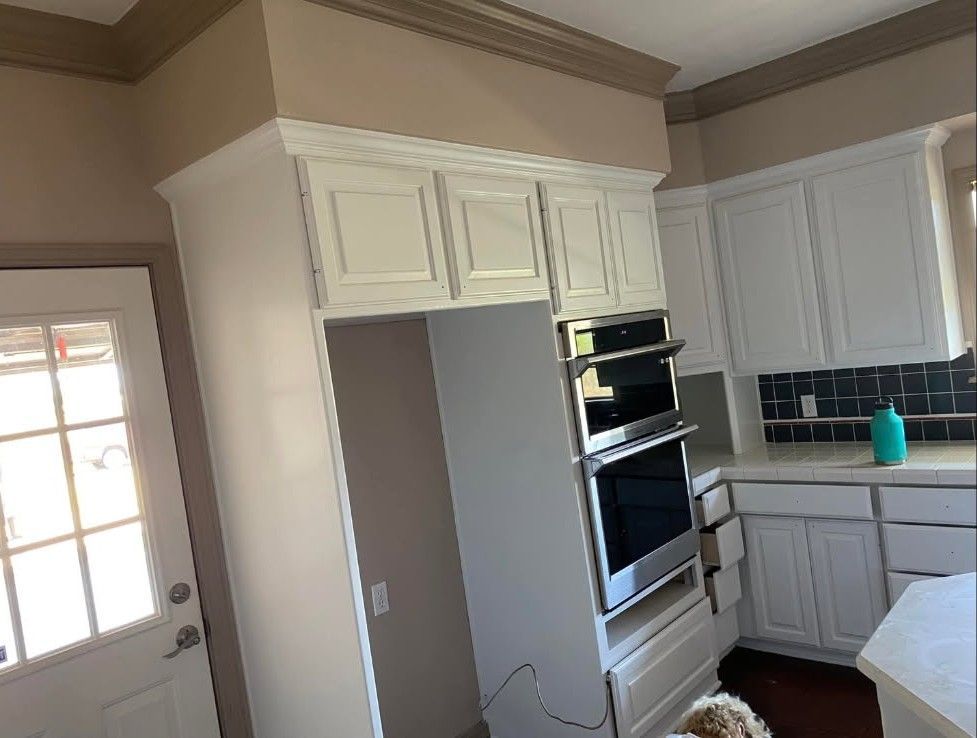 Kitchen with white cabinets, built-in ovens, and a refrigerator space. Light-colored walls and trim.