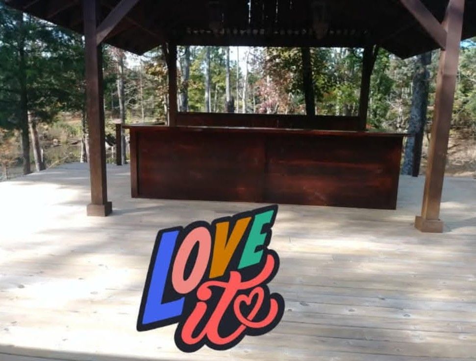 A dark wood bar inside a gazebo overlooking a forest, with 