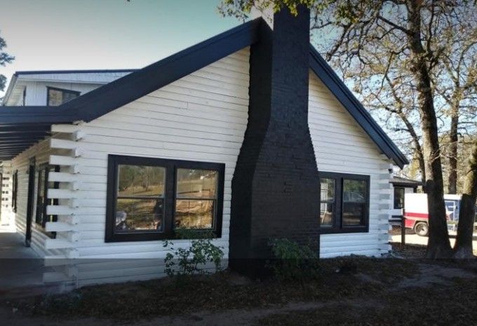 White cabin with black trim and chimney.