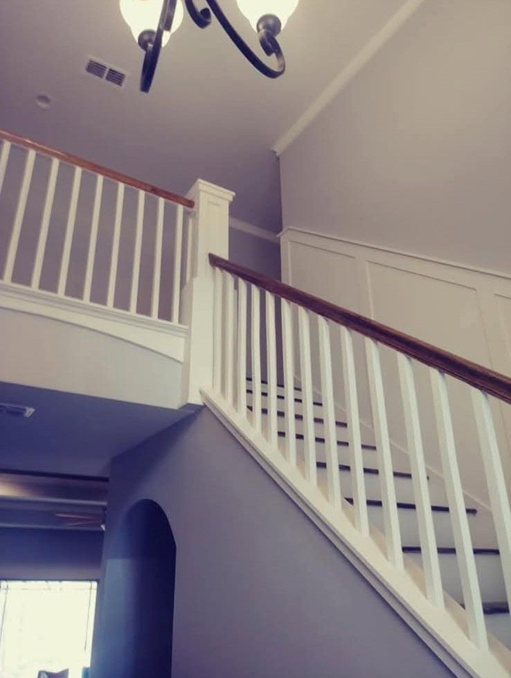 Staircase with white balusters and brown handrail against gray walls.