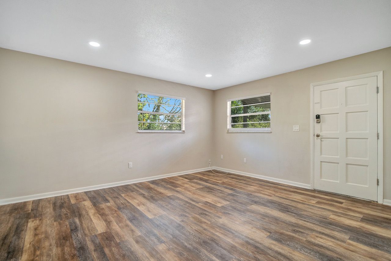 An empty living room with hardwood floors and a window.