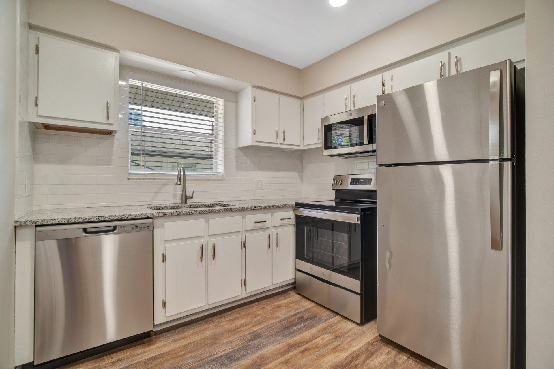 A kitchen with stainless steel appliances and white cabinets.