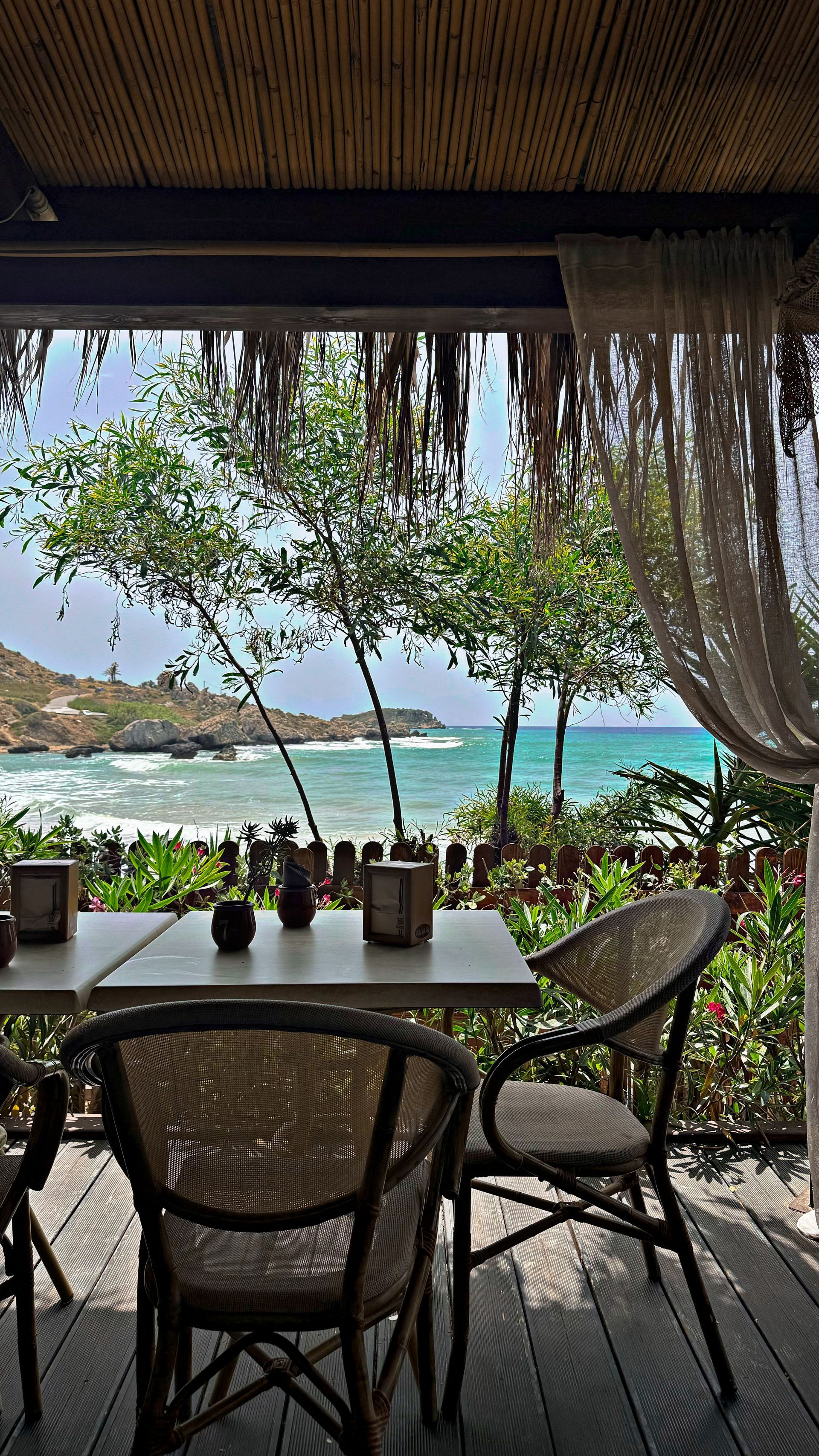 Un tavolo e delle sedie su un balcone con vista sull'oceano.
