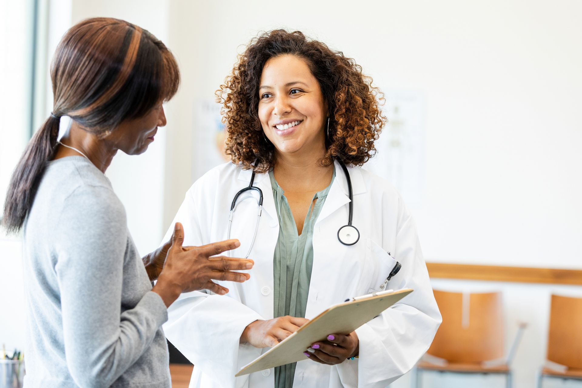Doctor in white coat smiles while talking to a patient in a clinic.