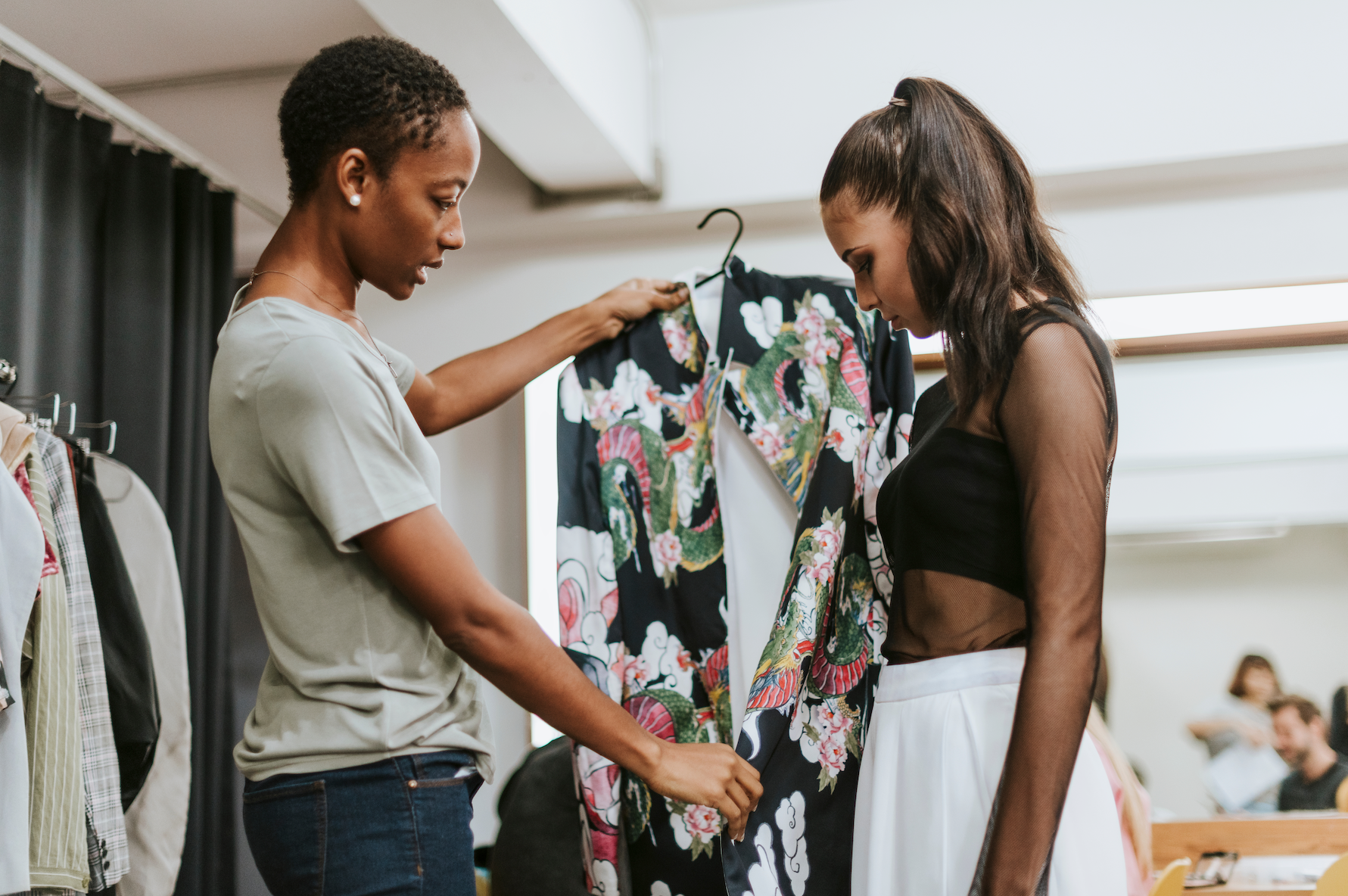 Two women are standing next to each other in a store looking at clothes.
