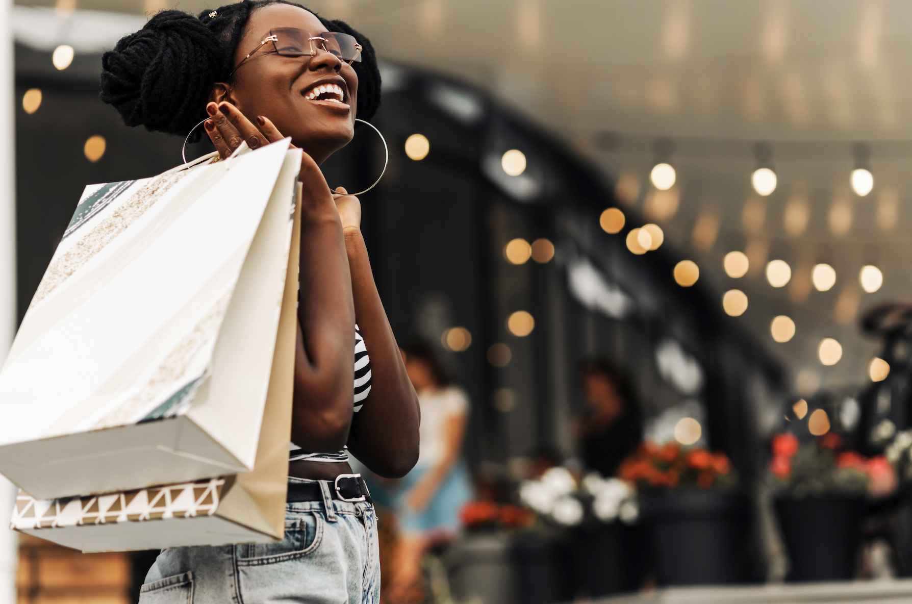 A woman is holding shopping bags in her hands and smiling.