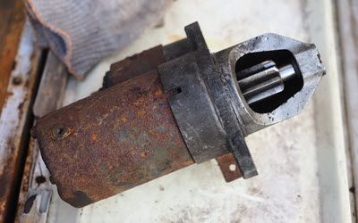A rusty starter motor is sitting on a white surface.  | Southwest Auto