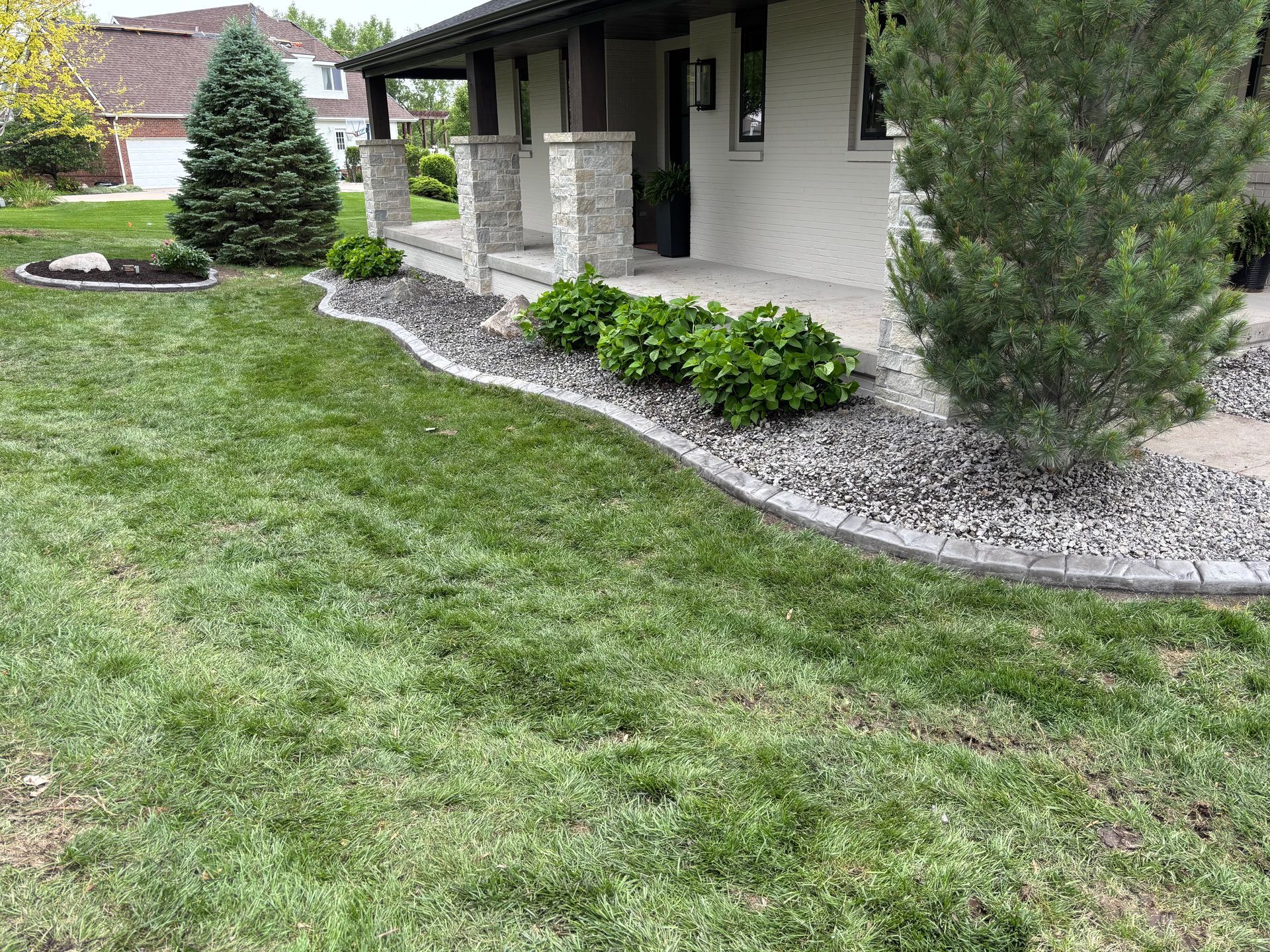 Green lawn with a house, flower beds, and porch.