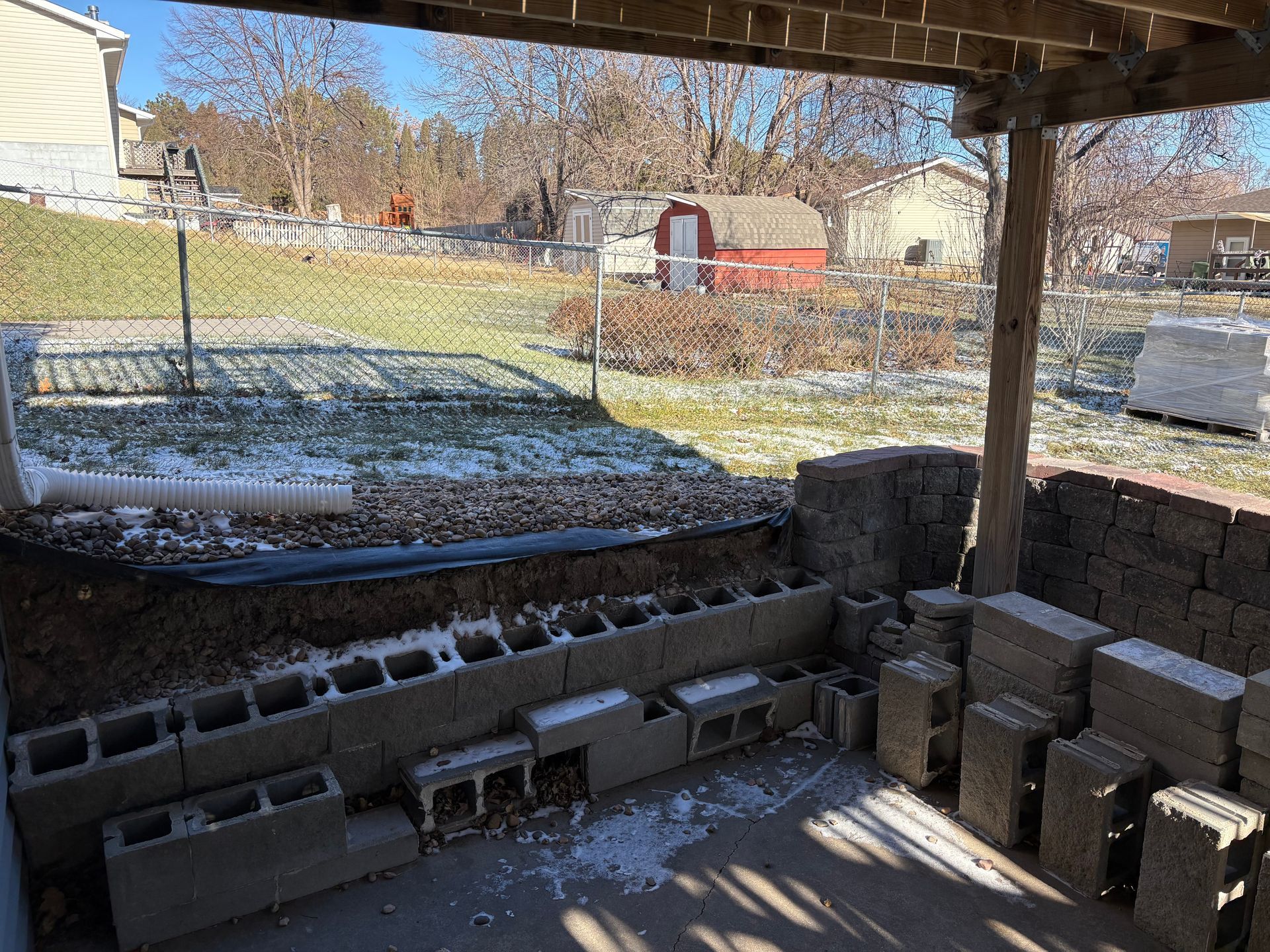 Backyard scene with cinder blocks, snow on the ground, and a small red shed.