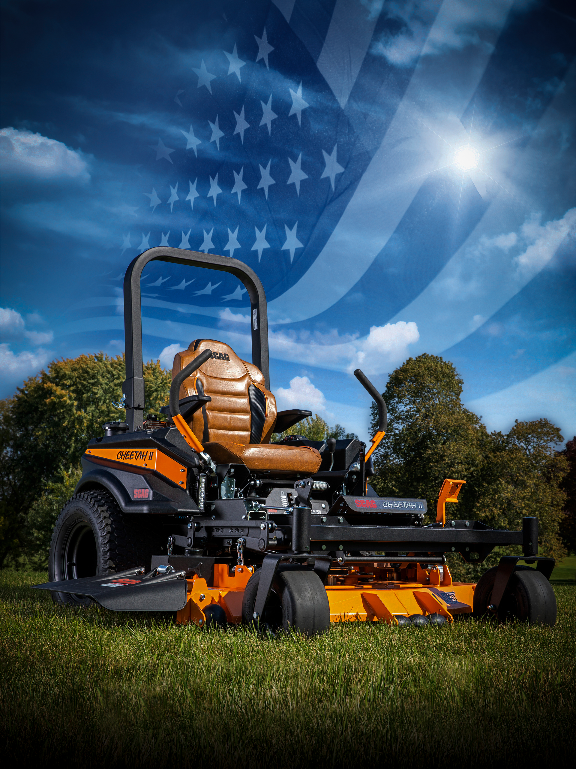 Orange and black riding lawnmower on grass with a waving American flag in the sky.