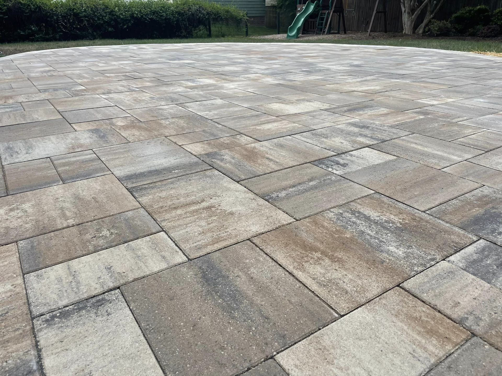 Stone patio with rectangular and square pavers in various shades of gray and brown.