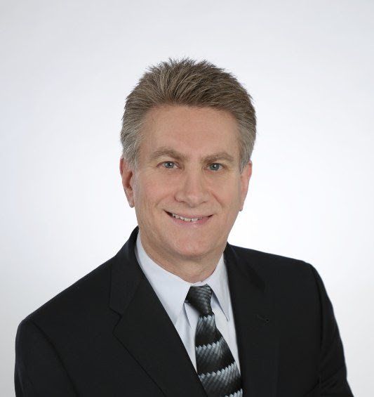 A man in a suit and tie is smiling for the camera