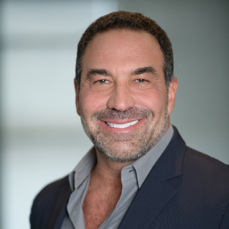 A man with a beard is wearing a suit and smiling for the camera.