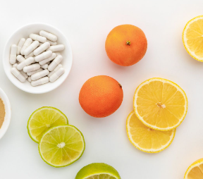 A bowl of pills surrounded by oranges lemons and limes