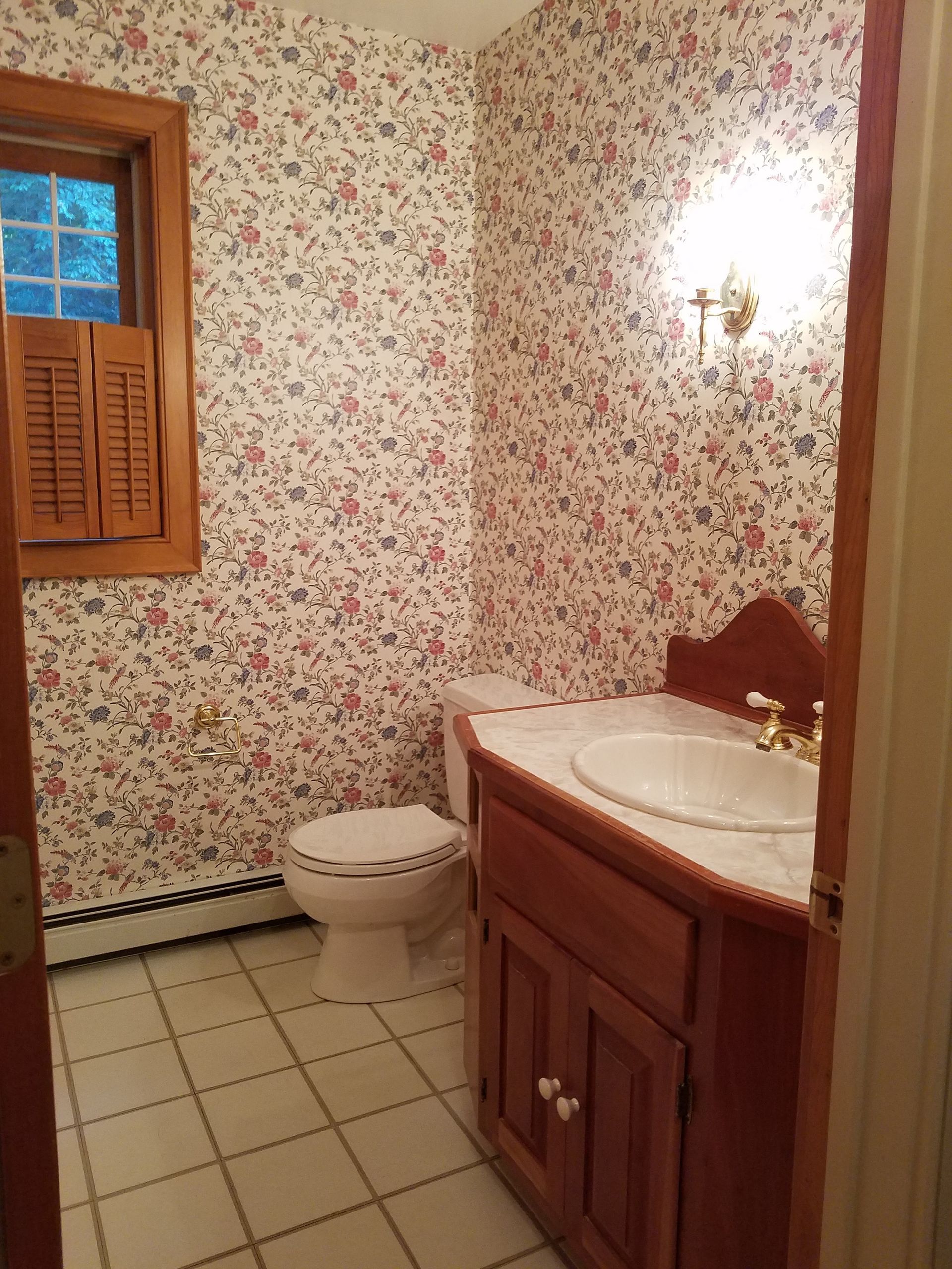 A bathroom with a toilet , sink and floral wallpaper