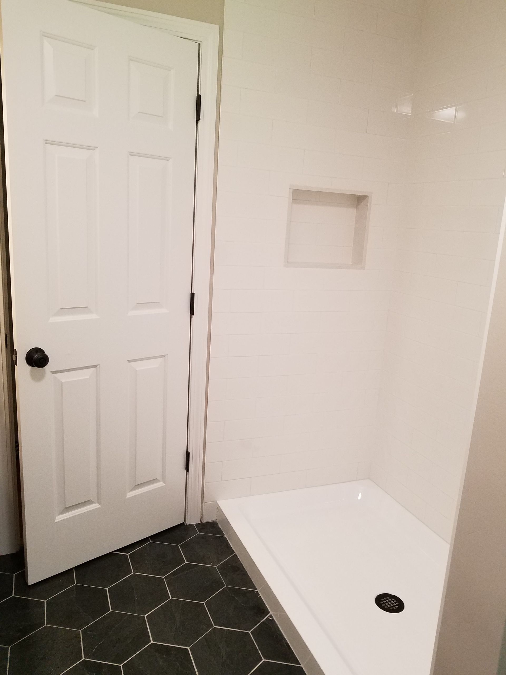 A bathroom with a shower stall and a door.