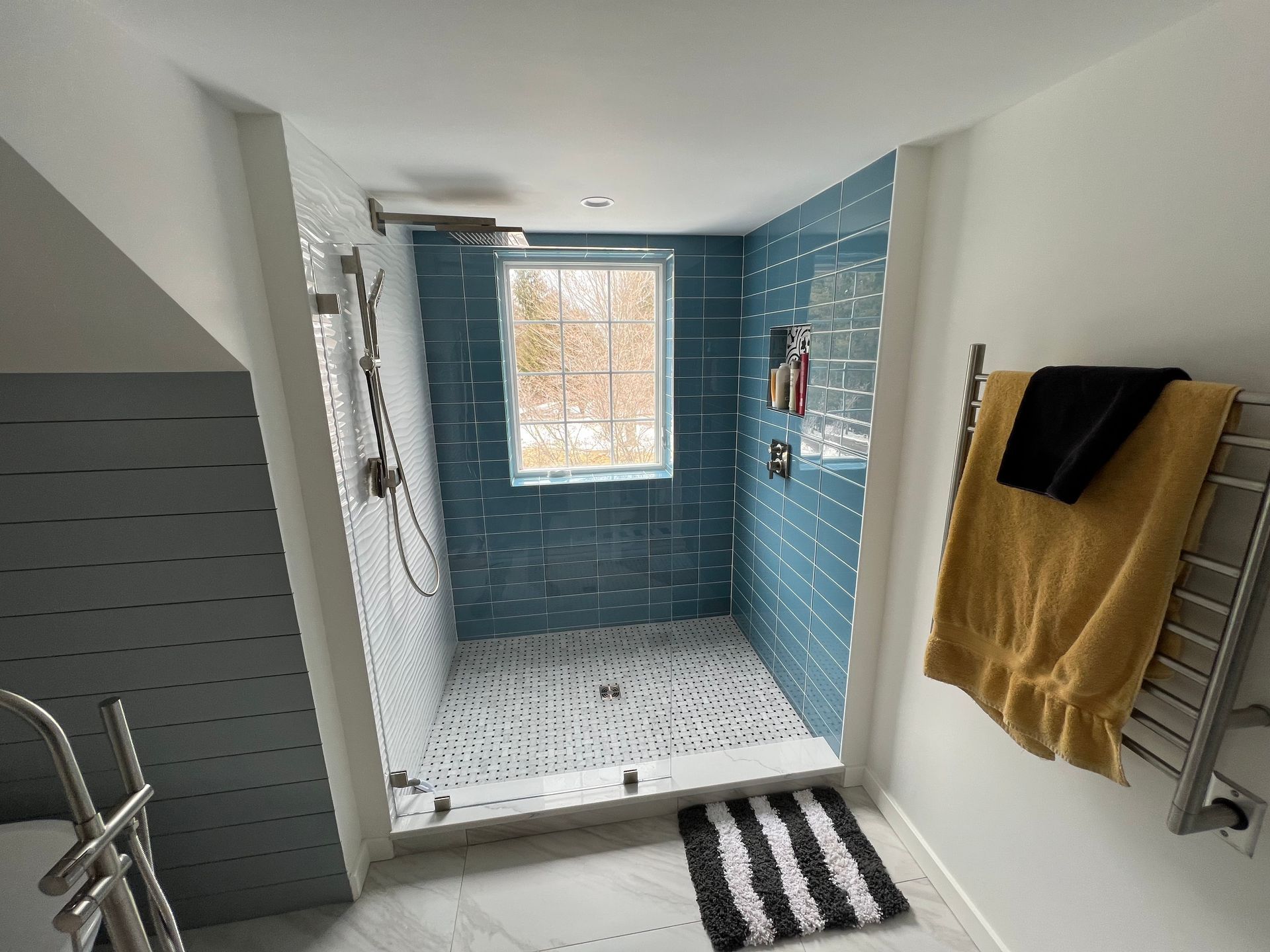A bathroom with a walk in shower and a window.