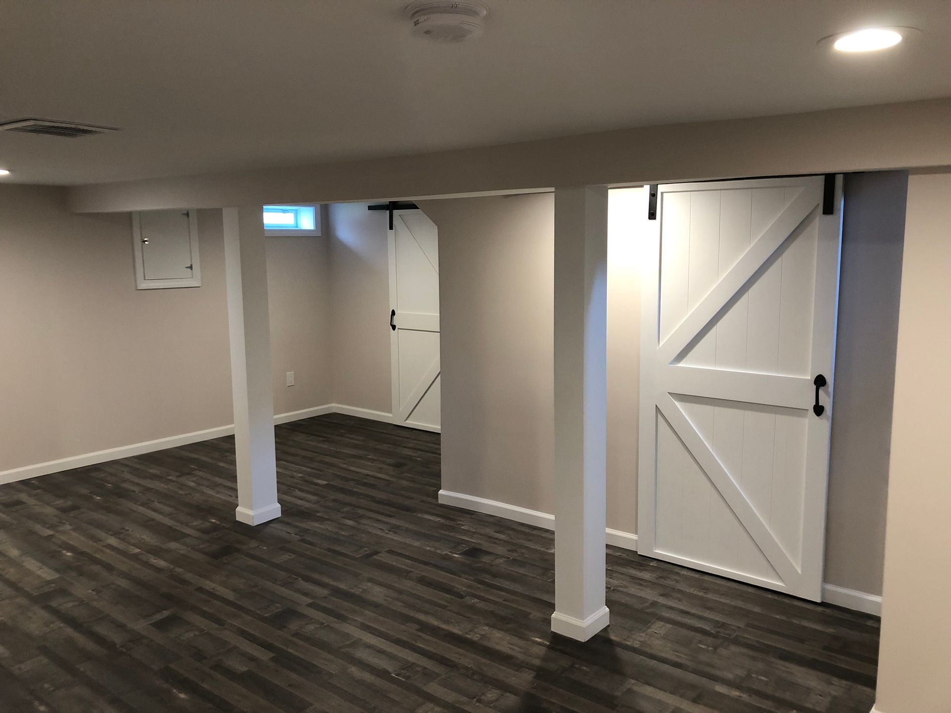 A basement with sliding barn doors and wooden floors
