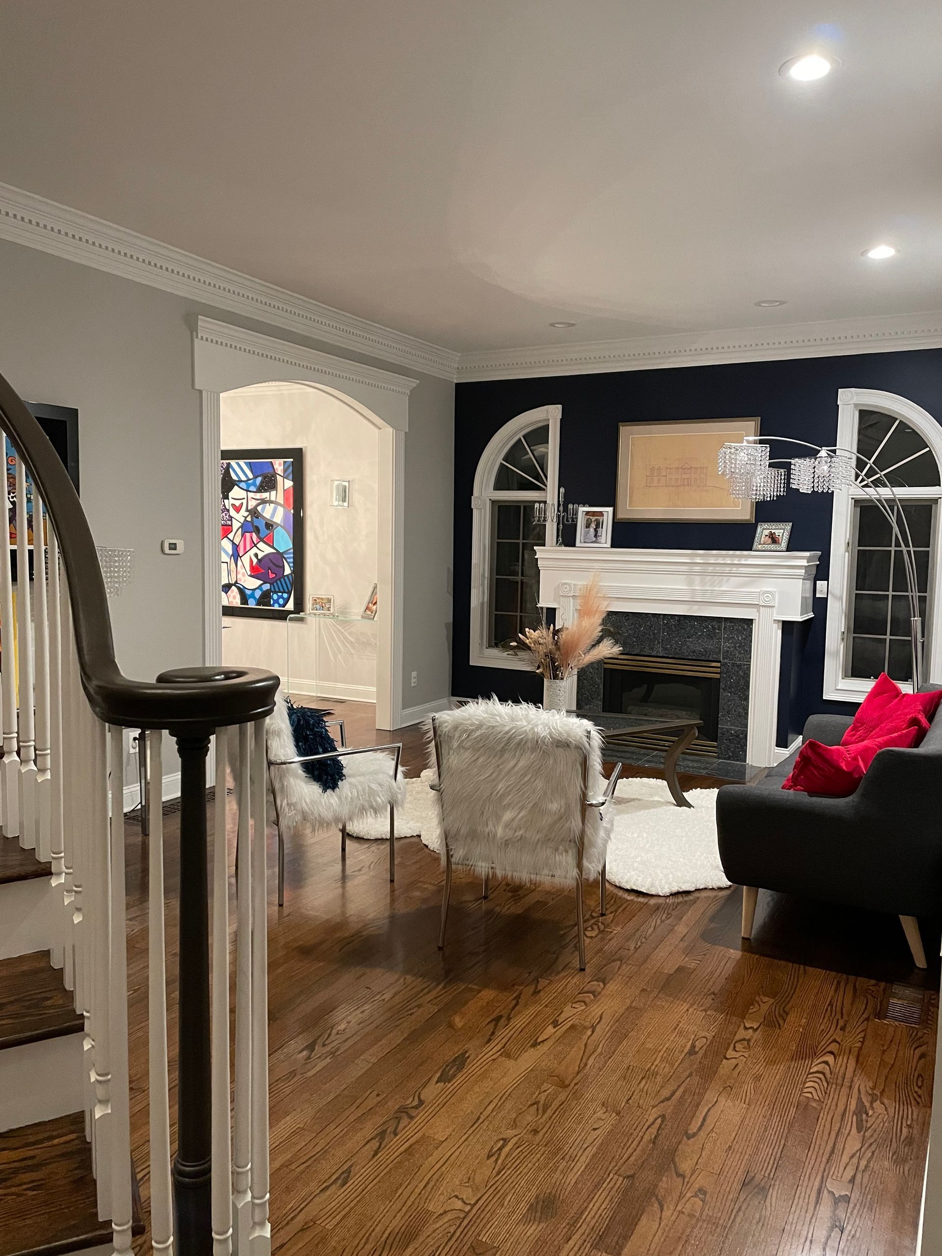 A living room with a fireplace , couch , chairs and stairs.