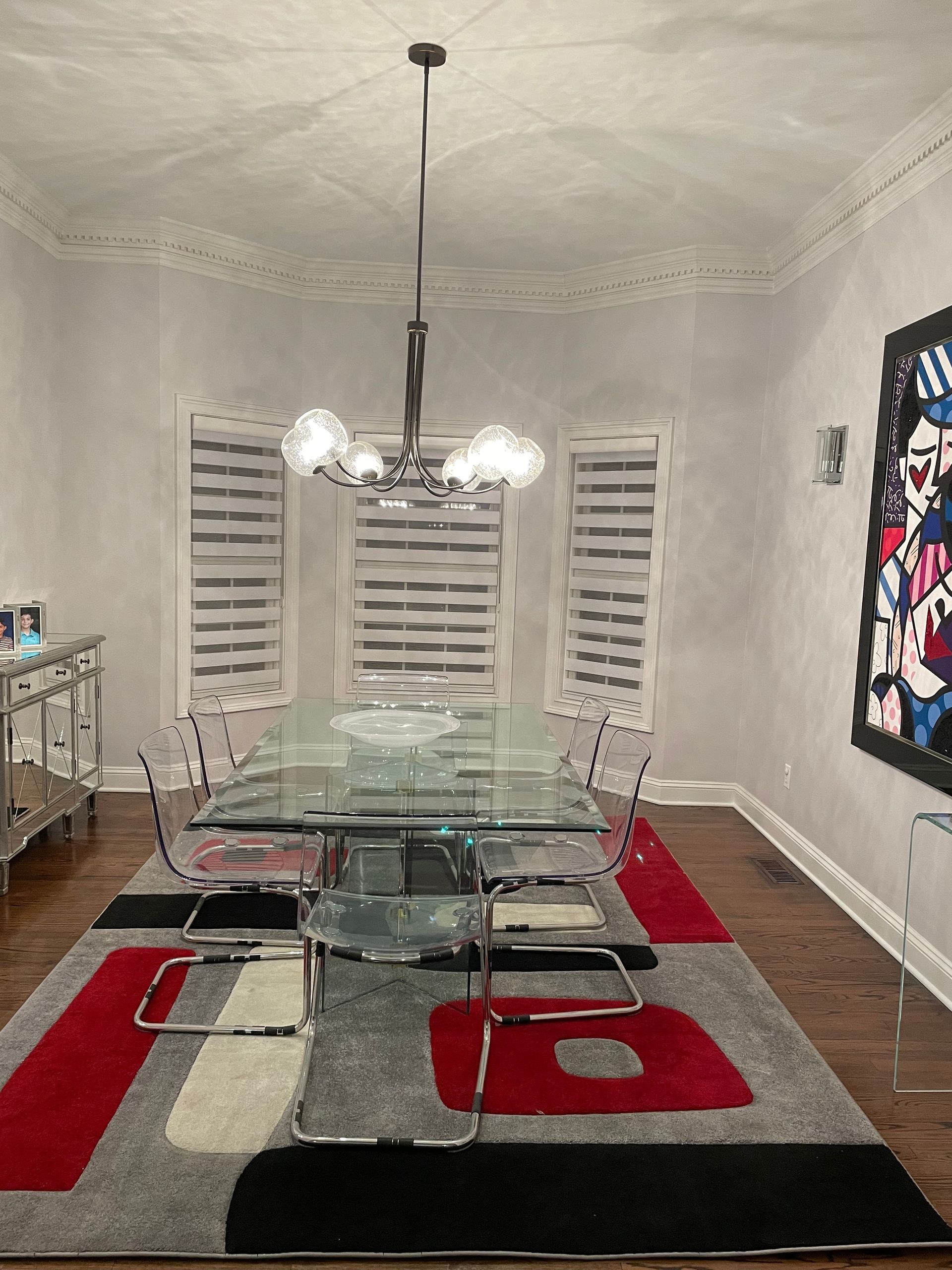 A dining room with a glass table and chairs and a rug.