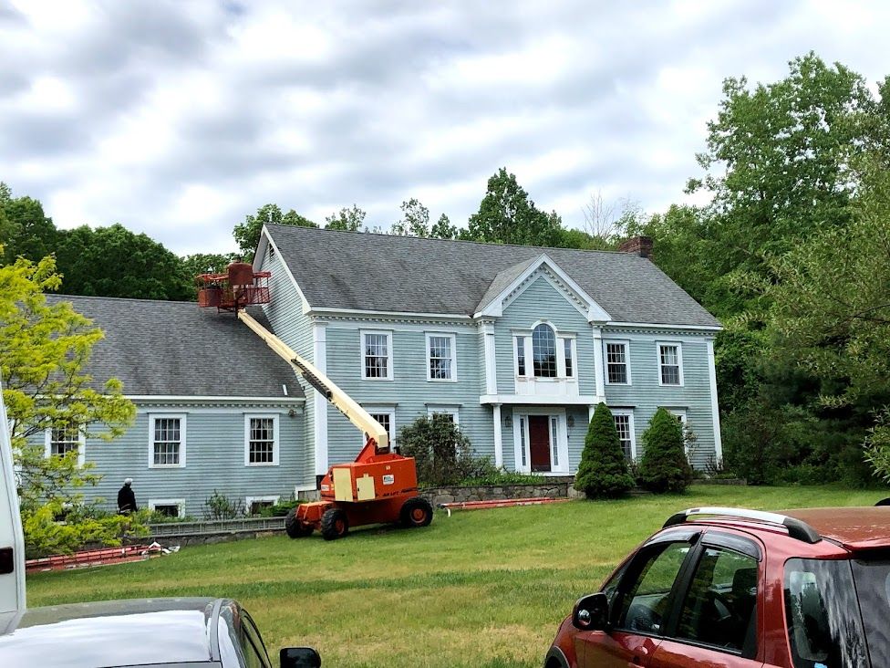 A large house with a roof lift in front of it.