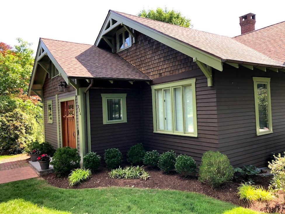 A brown house with a red roof and green trim