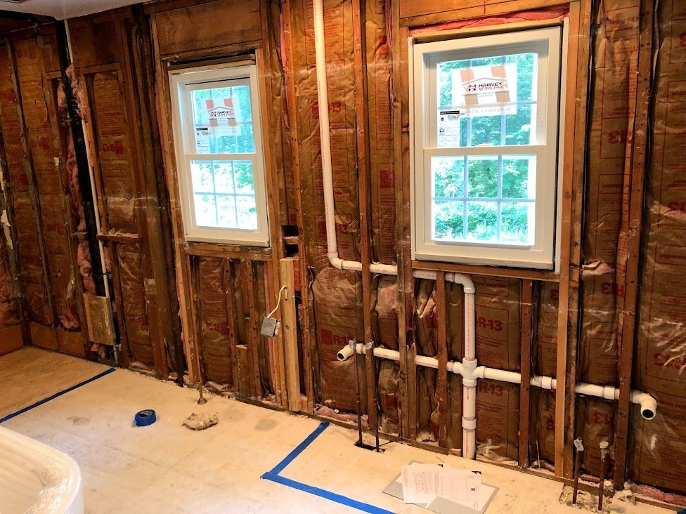 A bathroom under construction with a tub and two windows.