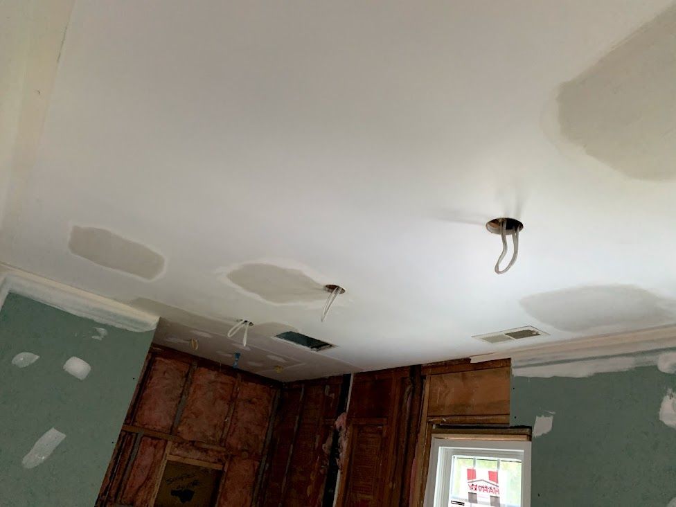 A kitchen under construction with a white ceiling and wooden cabinets.