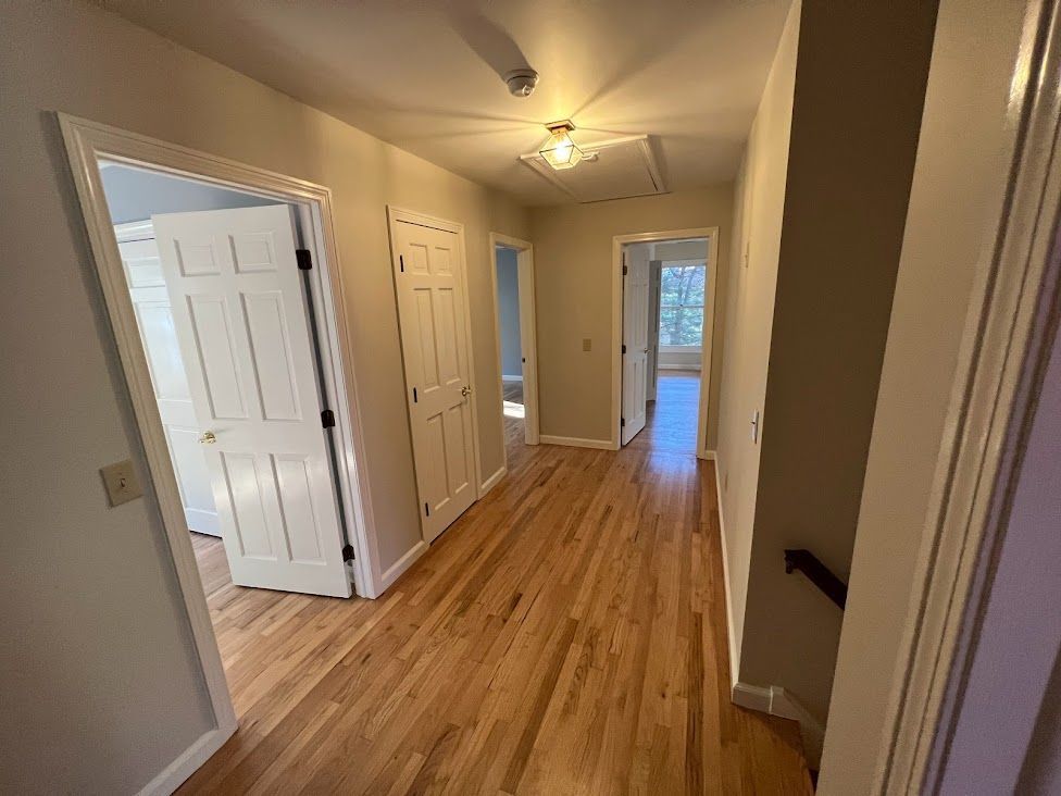 A hallway with hardwood floors and white walls in a house.