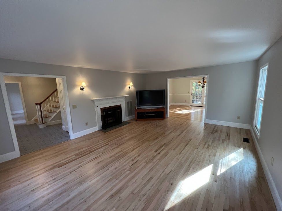 A living room with hardwood floors , a fireplace and a flat screen tv.
