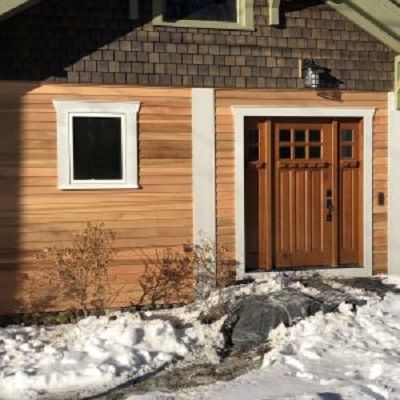 A house with a wooden door and a window in the snow