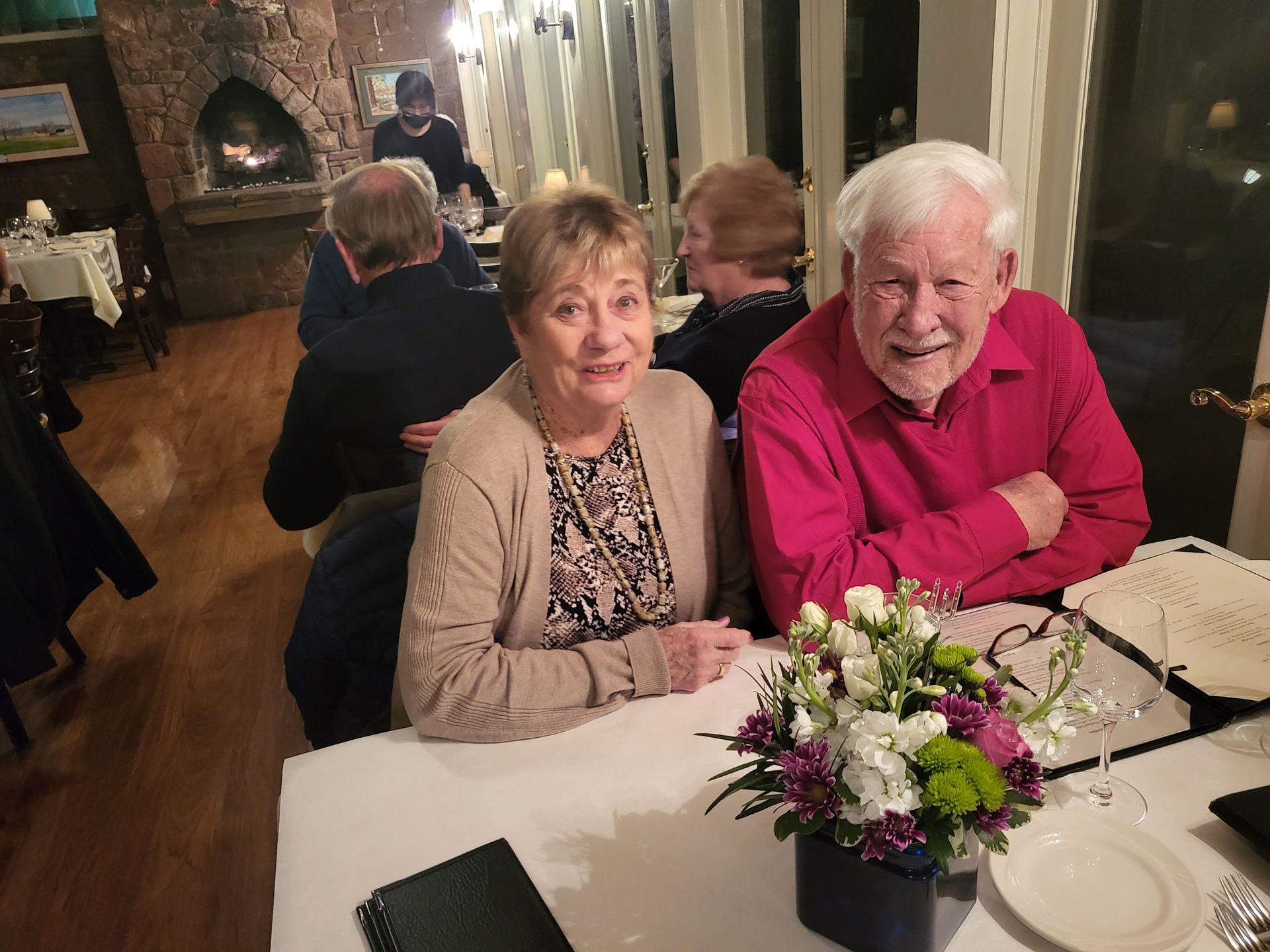 A man and woman are sitting at a table with flowers on it